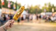 © Badru - Hand holding grilled corn on the cob at a summer festival