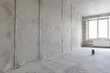 © milanchikov - Proceso de construcción en un espacio interior con paredes grises y una ventana grande a la luz natural