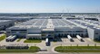 © YLing - Expansive modern automotive factory with solar panels on the roof and trucks at loading docks, captured from an aerial perspective on a clear day.