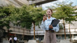© อภิสิทธิ์ ปักเหนือ - Young Businesswoman Looking at Smartphone with Office Documents Outdoors