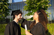© Cata - Graduates in caps and gowns celebrate outdoors, sharing joyful moments as a multiracial couple smiles together