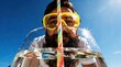 © ★★★★★ - Bearded man wearing diving mask peering through water glass outdoors. Sunny person with snorkel goggles and colorful straw under blue sky. Summer refreshment and holiday humor concept for travel.