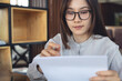 © tippapatt - Asian business woman reviewing business documents with laptop on table in modern office, workspace, focused remote work concept.