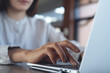 © tippapatt - Close up, business woman hands typing on laptop computer, working remotely in cafe or modern office,  online business lifestyle concept