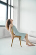 © Elena Kharichkina/Stocksy - Relaxed Woman Sitting on Wooden Chair in Soft Natural Light