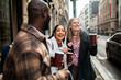 © Marko Geber - Friends laughing with takeaway coffee on city street