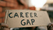 © photo for everything - Conceptual image of a person holding a cardboard sign with 'CAREER GAP' written on it, representing unemployment and job search challenges