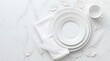 © Cressida - Elegant white plates stacked on marble with feathers.
