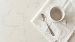 © arabelle - White coffee mug and silver spoon on marble tabletop.