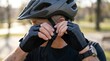 © Caius - Man fastening chin strap of black bicycle helmet.