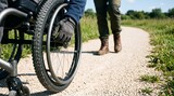 Wheelchair wheels cross a carefully maintained gravel trail
