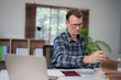 © Tj - Senior man working from home, organizing important documents and managing administration, reviewing financial reports and planning business strategy at his desk