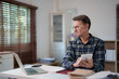 © Tj - Mature man concentrating on financial calculations, analyzing data with a calculator and laptop, managing his budget while working remotely at a home office desk