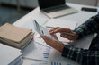 © Tj - Person is calculating finances and taxes, working on a business report with charts and graphs, and managing financial data for a company audit on a white desk