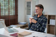 © Tj - Mature man working remotely from home office, taking a coffee break, enjoying flexible lifestyle and digital nomad freedom, balancing work and personal life