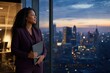 © WindJoy - Black businesswoman holding a tablet by an office window overlooking a city at dusk