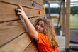 © Volodymyr - Adventure play creates happy childhood lifestyle. Adventure climbing supports young child confidence. Kid enjoys adventure on wooden wall. Playground activity makes adventure concept strong.