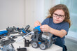 © Volodymyr - Child builds robot with focused hands. Child robotics supports smart STEM learning. Indoor portrait shows child engineering project. Creative toy develops child motor skills.