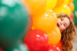 © Volodymyr - Child smiles among colorful balloons. Child peeks through festive decoration. Birthday balloons frame the child portrait. Bright colors surround the happy child.