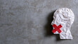 © A2Z AI  - Abstract image of a crumpled white paper head silhouette with a red cross tape on its mouth, symbolize silence, censorship, or lack of freedom of speech on a textured gray background with copy space