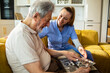 © Marko Geber - Caregiver helping senior man reminisce at home