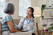 © Natee Meepian - Friendly female doctor offering compassionate care to senior patient during home medical visit
