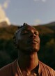 © CYBERPINK - Close-up portrait of a young african-american man with his eyes closed and his head tilted upwards. he appears to be in a peaceful and serene state, with a slight smile on his face.