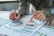© HappyEva - ESG investment sustainable finance concept, professional hands using calculator and pen for environmental performance metrics and carbon footprint corporate responsibility report analysis.