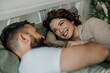 © La Famiglia - Couple smiling and talking in bed together