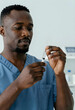 © Pixel-Shot - African american male healthcare worker in blue scrubs preparing a syringe with medication for injection, the medical professional is focused on the task, ensuring accuracy and safety