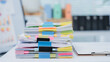 © Kritdanai - Workplace Documentation: A close-up shot of an office worker in a tailored blue blazer, meticulously reviewing a stack of documents.