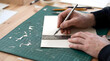 © Andres Mejia - Craftsman cutting paper with craft knife and ruler