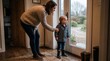 © haris - Mother comforts her young son as he looks out a glass door on a rainy day.