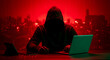© photo_grab - Anonymous hacker in hoodie using laptop for cyber attack in dark red neon city background