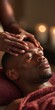 © Andrii Zastrozhnov - Closeup black man receiving forehead facial massage in warm candlelit spa for wellness background and banner design promoting relaxation and self care