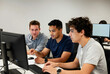 © Pixel-Shot - Diverse group of male students collaborating on a computer project in a modern classroom setting, One student points at the screen, indicating discussion and teamwork