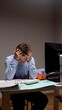 © Aliaksandr - Young man sitting at his desk late at night, holding his head in his hands, feeling exhausted and pressured by work overload in a corporate setting