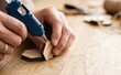 © SimpleDesignStudio - Close up of a man gluing small wooden hexagons with a glue gun for a craft project