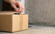© SimpleDesignStudio - Unpacking a parcel delivery box at doorstep by hand representing online shopping and home delivery