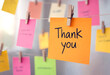 © DesignArt - Bright orange sticky note with thank you message hanging among colorful notes and clips
