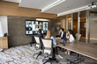 © fizkes - Businesspeople collaborating with multiethnic colleagues through video call on digital screen in corporate boardroom. Global business communication, team negotiation, technology, virtual work meeting