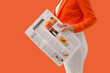© Pixel-Shot - Woman in orange blazer and white pants holding a fashion newspaper with articles on urban trends and new styles, the publication features various images and text, current fashion information and media