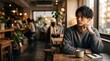 © Mayu2 - カフェの窓際でコーヒーを飲みながら佇むおしゃれな若い男性