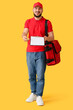 © Pixel-Shot - Male worker of food delivery service with bag and clipboard on yellow background