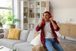 © Pixel-Shot - Young man in headphones sitting on sofa at home