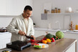 © Pixel-Shot - Young man cutting tomato at table in kitchen