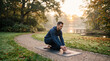 © Matos - Man practicing yoga on a mat in a park during sunrise with autumn leaves