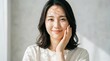 © dadi - Young Asian woman gently touching cheek smiling softly in bright natural light portrait