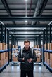© AdPremium - Male warehouse manager using a digital tablet to control automated robots in a modern distribution center with high-tech inventory shelves