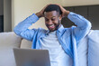 © simona - Smiling man relaxing on a couch with a laptop, celebrating good news while working from home and enjoying remote work, happiness and casual productivity